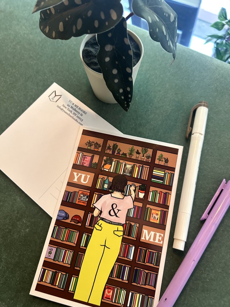 The Just Browsing, Yu & Me Post Card by Yu & Me Books is a glossy illustrated postcard showing someone browsing the bookstore, displayed on a green surface with an envelope, white potted plant, purple pen, and white marker.