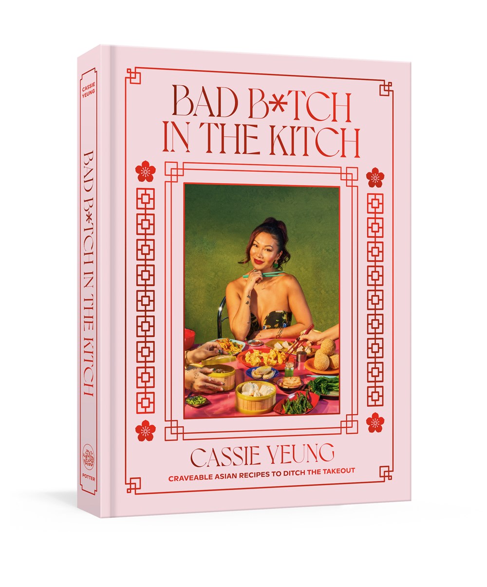 Book cover of "Bad B*tch in the Kitch by Cassie Yeung (Signed!)," available from Yu & Me Books, shows a woman in a red dress at a table of Asian dishes on a green background with pink and red borders.