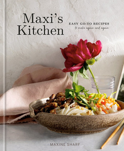 The cover of Maxi’s Kitchen by Maxine Sharf (Signed! Limited Qty), available from Yu & Me Books, displays a bowl with noodles, vegetables, and meat, a pink napkin, red peony, and water glass—welcoming you to easy, tasty recipes.