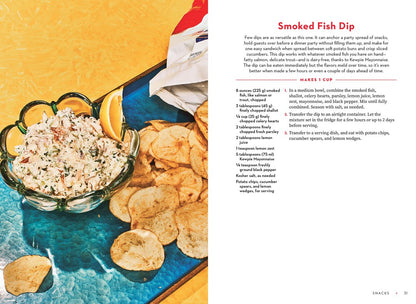 A bowl of smoked fish dip made with For the Love of Kewpie by Elyse Inamine & Jessie YuChen (Signed) from Yu & Me Books is garnished with herbs and lemon, served with ridged chips, cucumber spears, and lemon wedges.