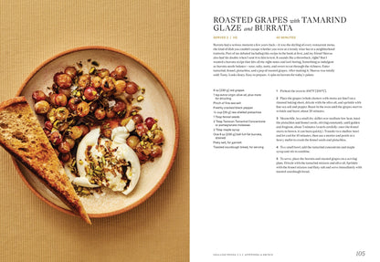 A plate of roasted grapes with seeds, herbs, burrata, and toasted bread sits on a tan surface. Recipe text for Indian-inspired roasted grapes with tamarind glaze from "East to East by Rachel Gurjar" (Yu & Me Books) appears beside it.