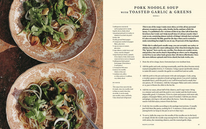 Two ornate bowls of pork noodle soup topped with cilantro, onions, and greens rest on a tan surface; at right is a recipe for Pork Noodle Soup with Toasted Garlic & Greens inspired by Something from Nothing by Alison Roman (Signed!) from Yu & Me Books.