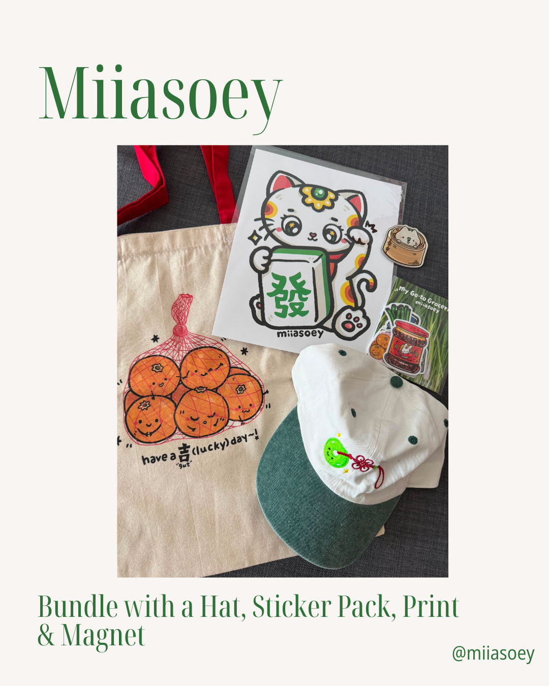 A bundle featuring a green and white hat, sticker pack, lucky cat print, magnet, and an orange character tote—all arranged on a table—perfect for fans of NYC culture. Text: [Raffle] Support Village Works Bookstore! Bundle by Yu & Me Books.